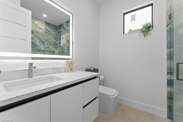 Bathroom featuring Large vanity, a stall shower, toilet, and baseboards
