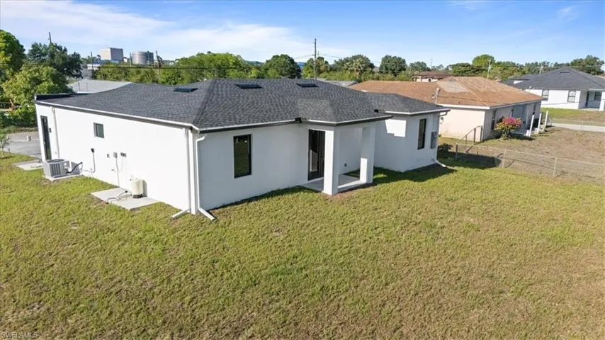 Rear view of property featuring stucco siding, a shingled roof, and central air condition unit