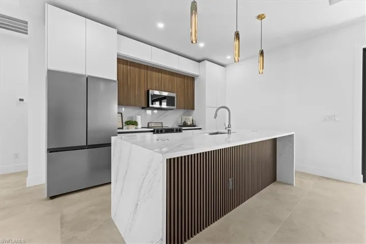 Kitchen with appliances with stainless steel finishes, a sink, modern cabinets, beige cabinets, and recessed lighting