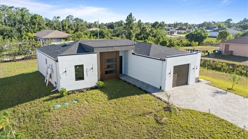 View of front facade with a front lawn, roof with shingles, stucco siding, and driveway