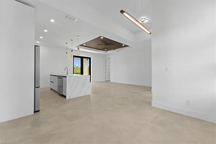 Tray ceiling, recessed lighting, a sink, matte tile flooring, and baseboards