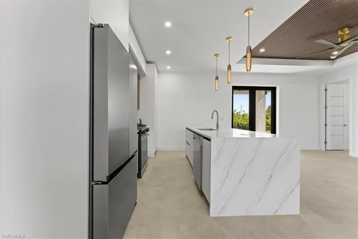 Kitchen featuring modern cabinets, a sink, recessed lighting, and a kitchen island with sink