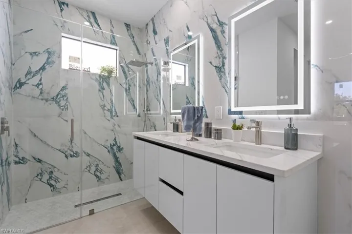 Bathroom with a marble finish shower and double vanity