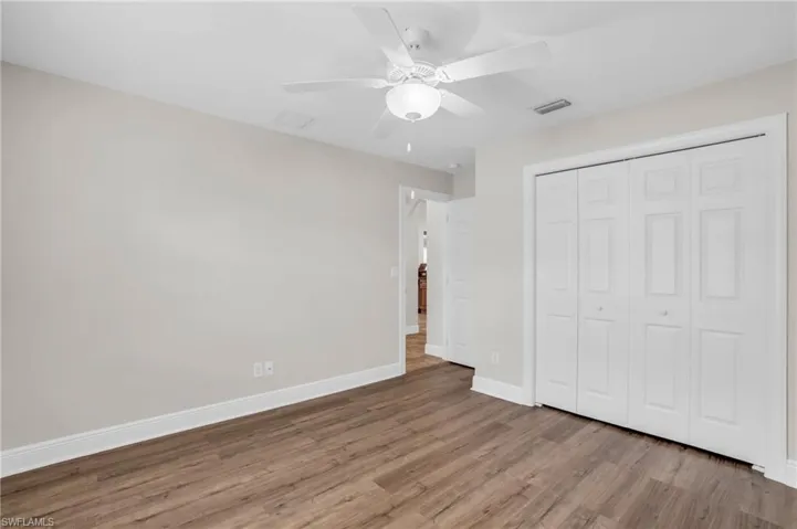 Unfurnished bedroom featuring ceiling fan, a closet, and wood-type flooring