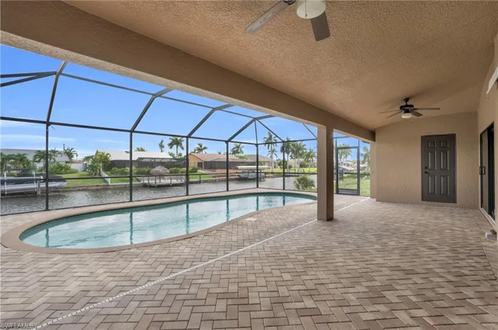 View of pool with a lanai, a patio area, and ceiling fan