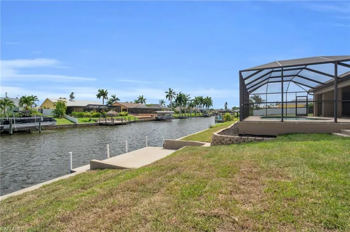 Dock area featuring a yard, glass enclosure, and a water view