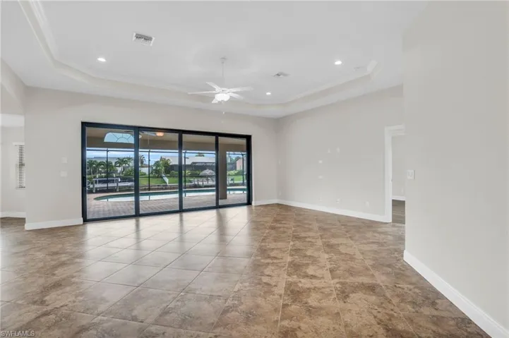 Unfurnished room with a tray ceiling, ceiling fan, and light tile floors