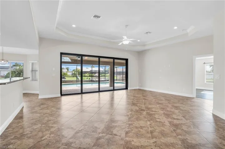 Tiled empty room with a tray ceiling and ceiling fan