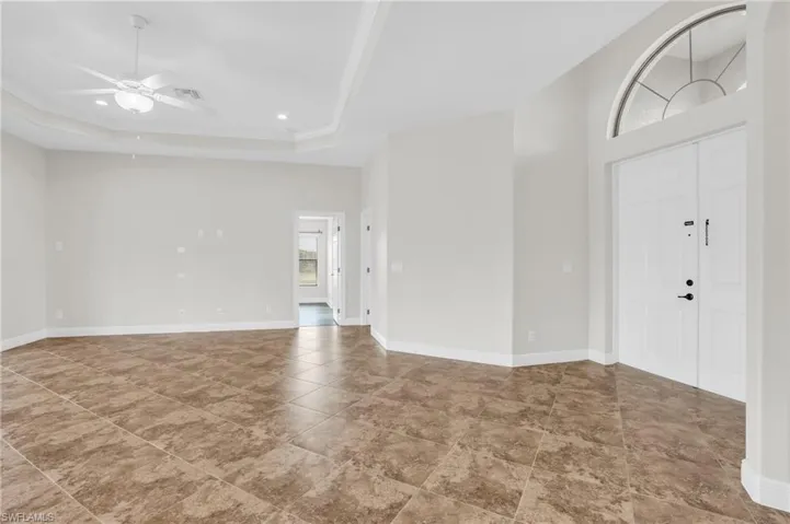 Tiled foyer entrance with a raised ceiling and ceiling fan