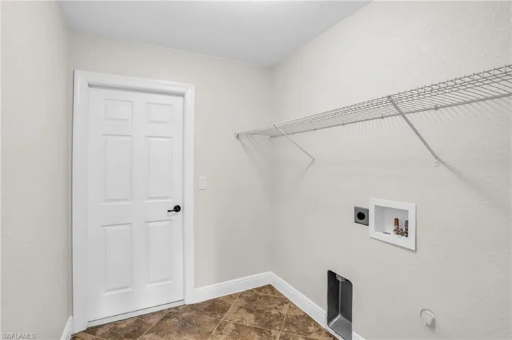 Laundry area with hookup for a washing machine, electric dryer hookup, and dark tile floors