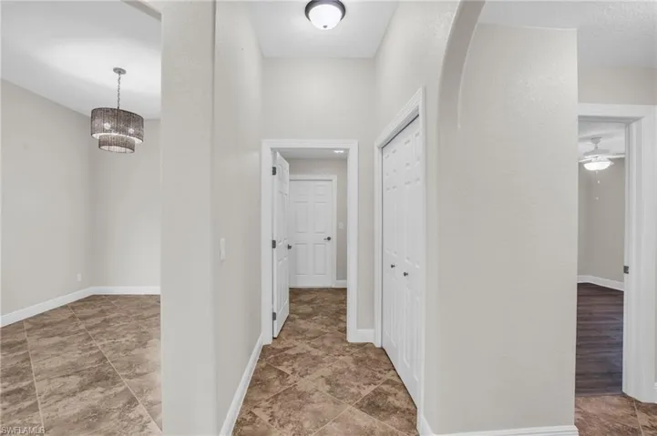 Corridor featuring a notable chandelier and tile flooring