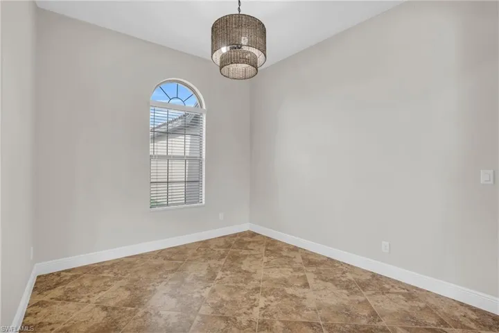 Tiled spare room featuring an inviting chandelier