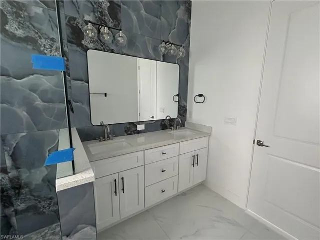 Primary bathroom with marble tiles and double vanity