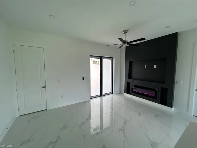 Living room featuring a ceiling fan, a glass covered fireplace, light marble finish flooring, and recessed lighting