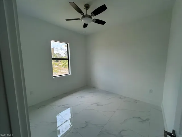 Bedroom with marble look tile flooring, ceiling fan, and baseboards