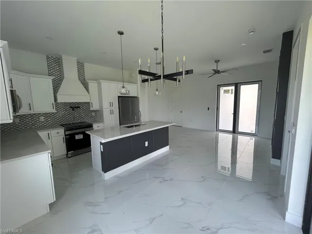 Kitchen with custom range, a sink, a ceiling fan, and decorative backsplash
