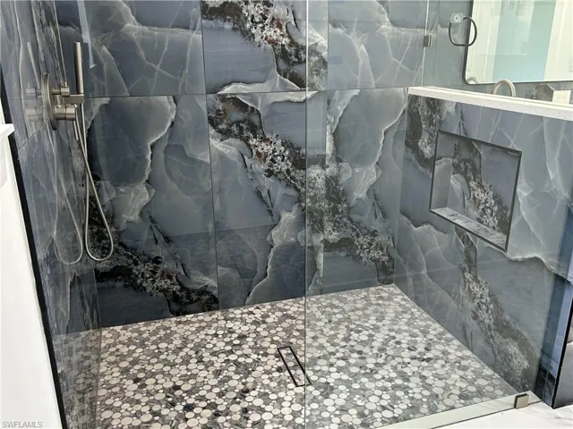 Primary bathroom featuring a marble finish shower and niche