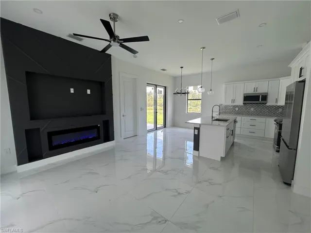 Open floor plan, decorative backsplash, and a glass covered fireplace