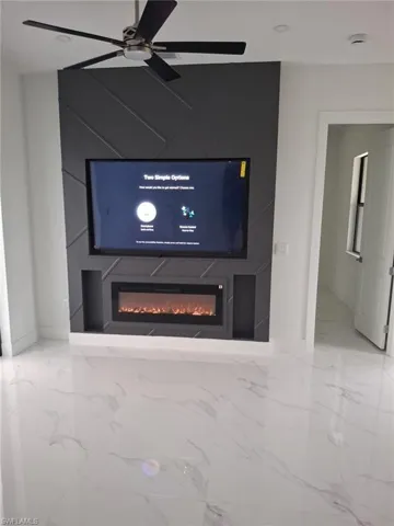 Detailed view of a glass covered fireplace, baseboards, a smoke detector, and a ceiling fan