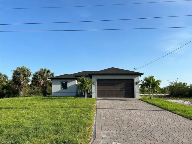 View of front of home featuring stucco siding, decorative driveway, an attached garage, and a front yard