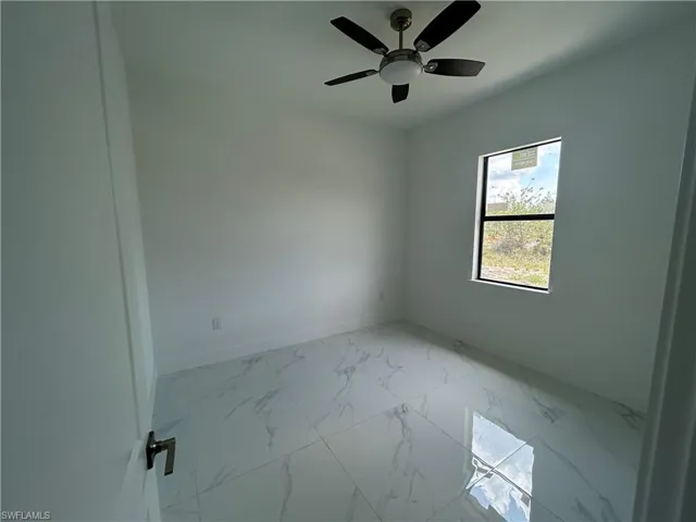 Bedroom featuring baseboards, light marble finish flooring, and a ceiling fan