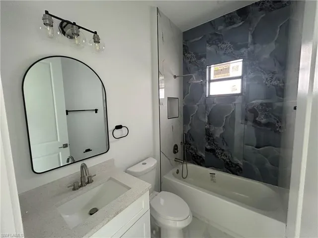 Bathroom with toilet, vanity, and bathtub / shower combination