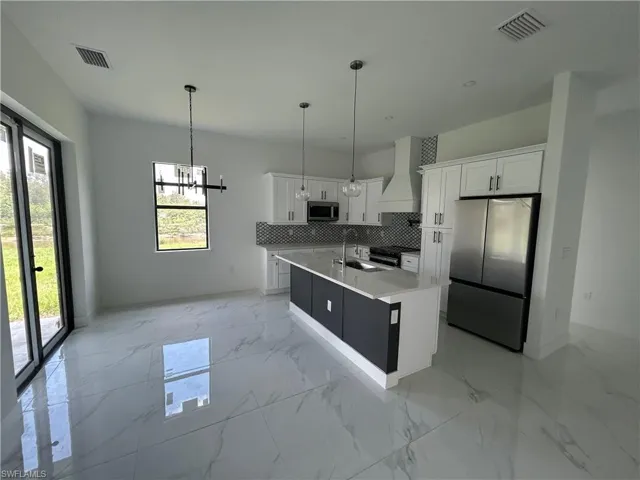 Kitchen with stainless steel appliances, exhaust hood, and white cabinetry