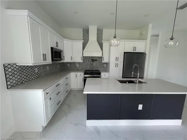 Kitchen with range hood, stainless steel appliances, a sink, and white cabinetry