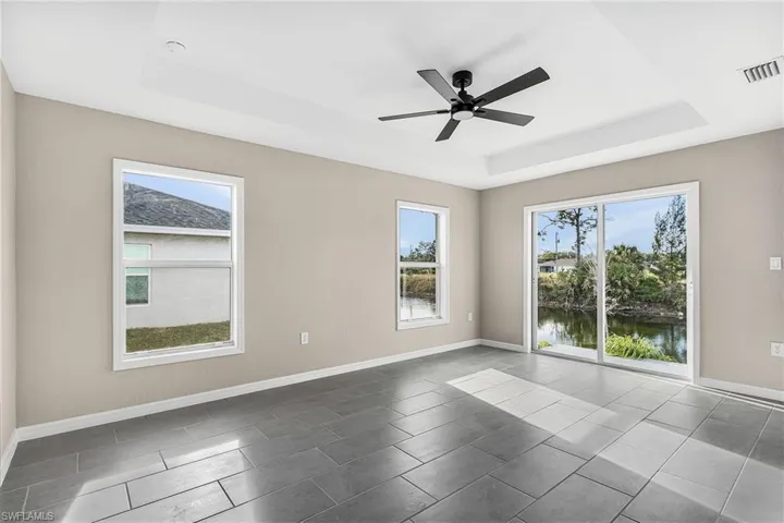 Spare room with a ceiling fan, a water view, and a raised ceiling