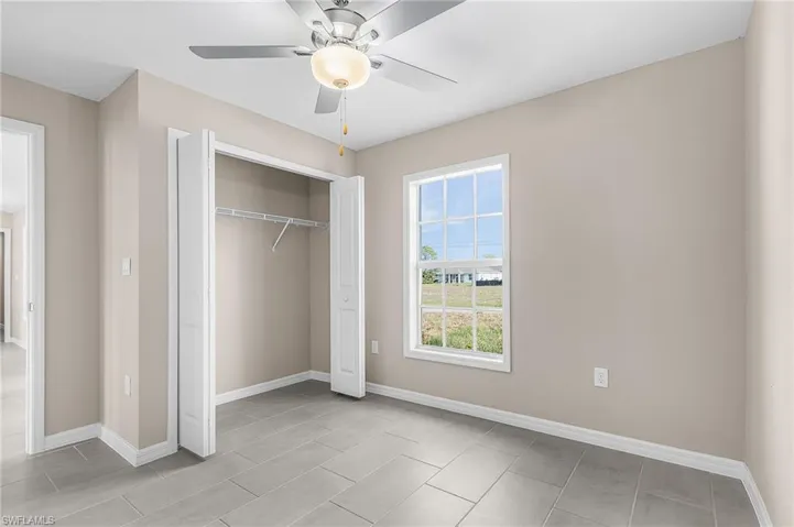 Unfurnished bedroom with ceiling fan and a closet