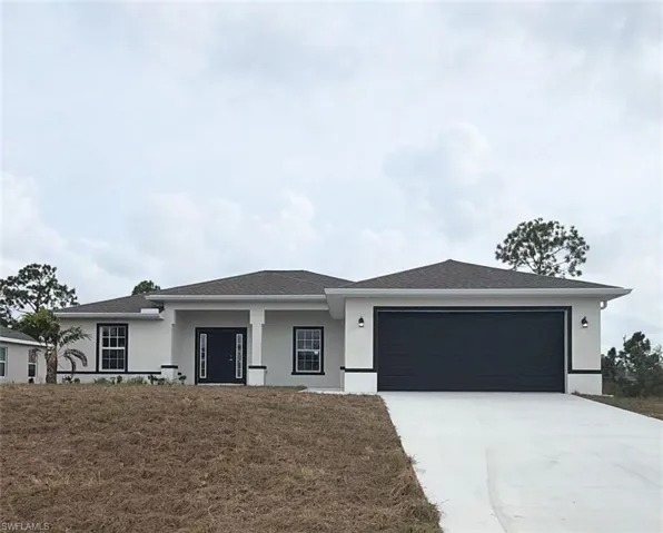 View of front of property with stucco siding, driveway, an attached garage, and a front lawn