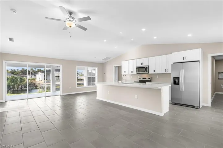 Kitchen featuring stainless steel appliances, white cabinetry, a kitchen island with sink, a ceiling fan, and open floor plan