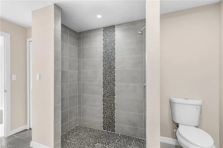 Full bathroom featuring a shower stall and toilet