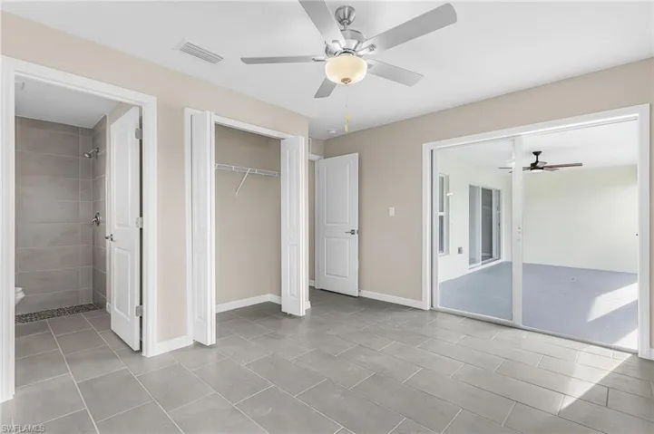 Unfurnished bedroom featuring a closet, ceiling fan, connected bathroom, access to outside, and light tile patterned floors