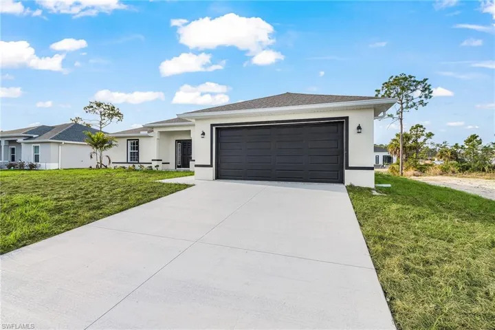 Ranch-style house with a front yard, stucco siding, concrete driveway, and a garage