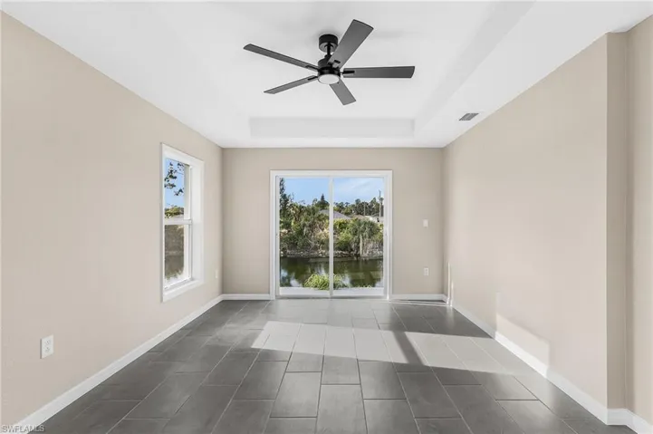 Unfurnished room with a tray ceiling, ceiling fan, and a water view