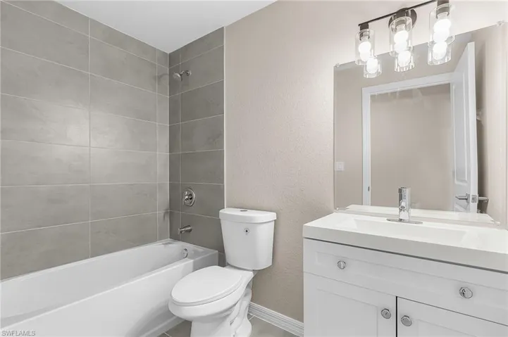 Full bath featuring a textured wall, vanity, and shower / bathtub combination