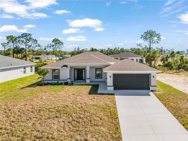 View of front of property with stucco siding, a shingled roof, driveway, an attached garage, and a front yard