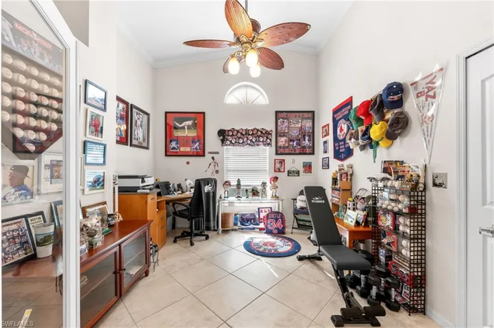 Office area featuring ornamental molding, ceiling fan, light tile patterned flooring, and a high ceiling