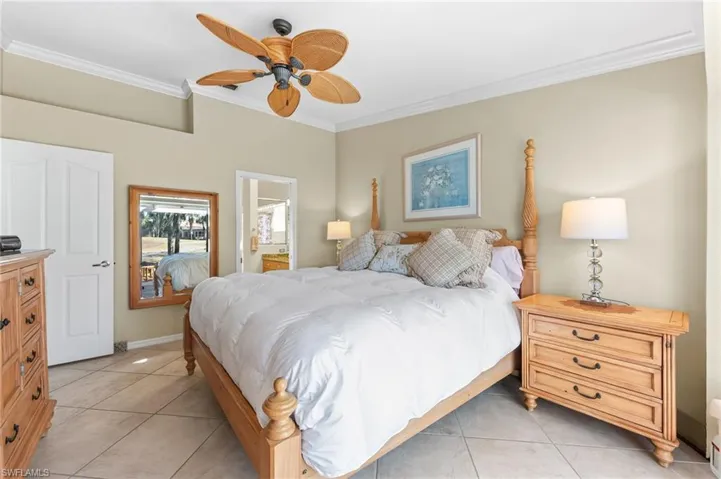 Bedroom with ornamental molding, a ceiling fan, connected bathroom, and light tile patterned floors