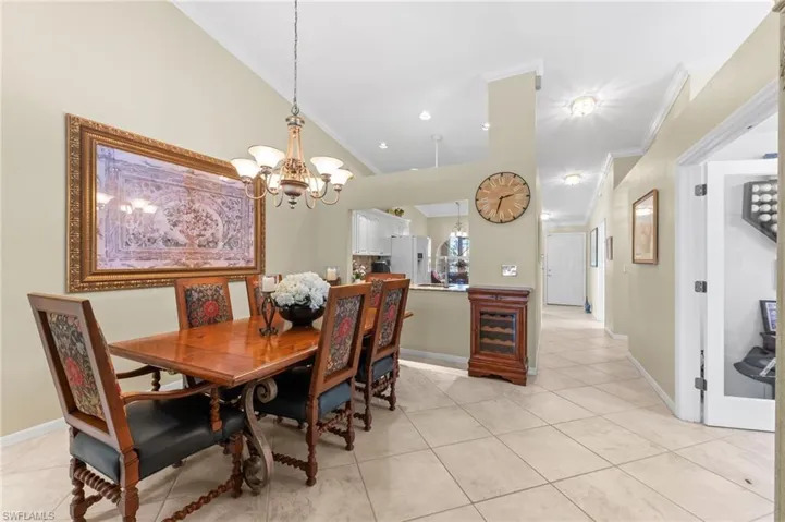 Dining room with hanging lights, light tile patterned flooring, ornamental molding, and vaulted ceiling