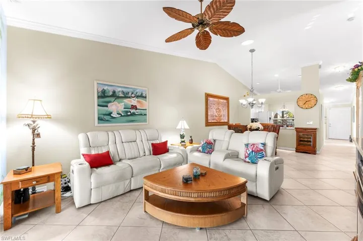 Living room with light tile patterned floors, suspended lighting, a ceiling fan, crown molding, and vaulted ceiling