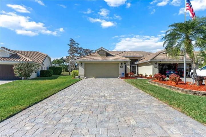 Ranch-style home with stucco siding, decorative driveway, a garage, a front lawn, and a tile roof