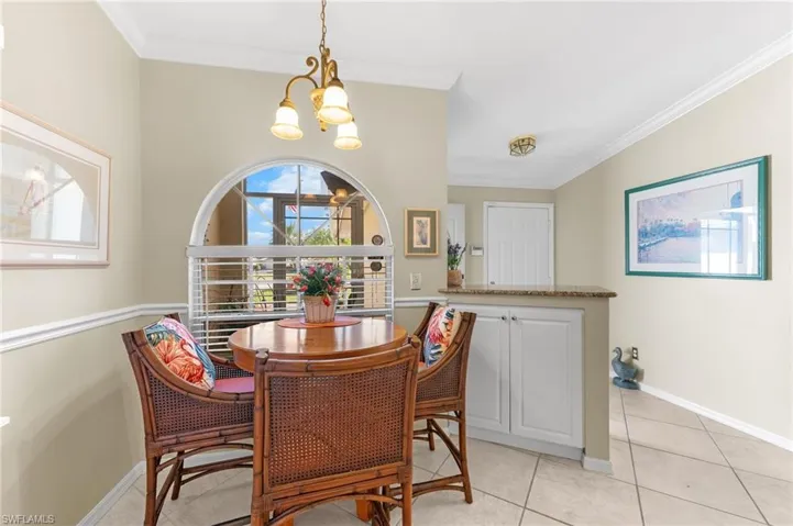 Dining area with crown molding, a chandelier, and light tile patterned floors