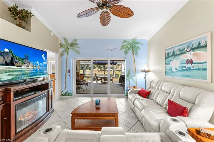 Living room featuring ornamental molding, a ceiling fan, and light tile patterned floors