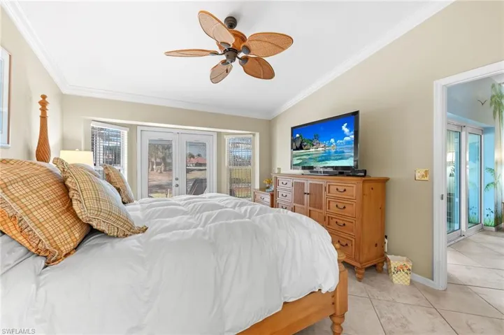 Bedroom featuring french doors, access to outside, a ceiling fan, lofted ceiling, and crown molding