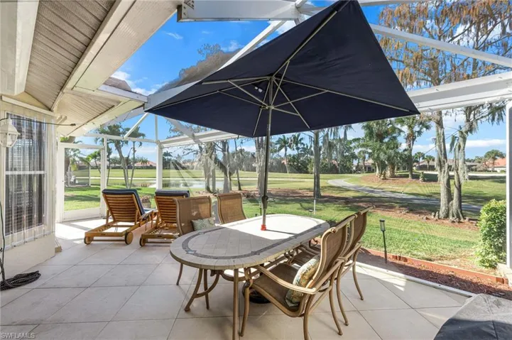 View of patio featuring a sunroom, outdoor dining area, and view of golf course