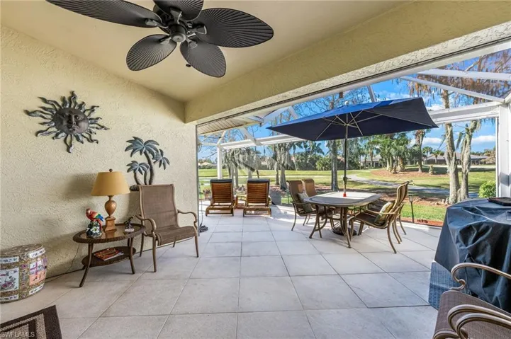 View of patio featuring a sunroom, glass enclosure, ceiling fan, view of golf course, and outdoor dining space