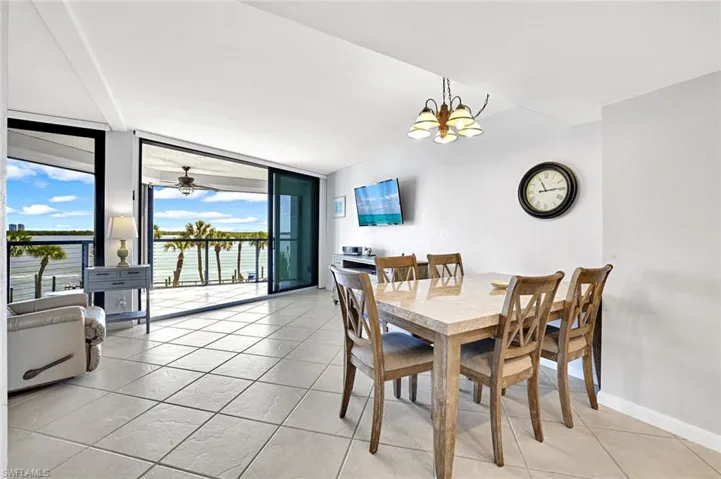Dining space featuring baseboards, floor to ceiling windows, an inviting chandelier, and light tile patterned flooring