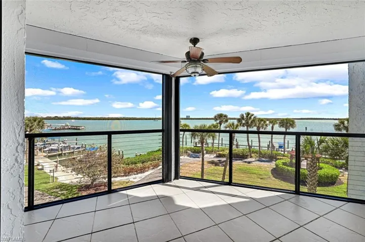 Unfurnished sunroom featuring tile patterned flooring, a water view, a healthy amount of sunlight, and a textured ceiling